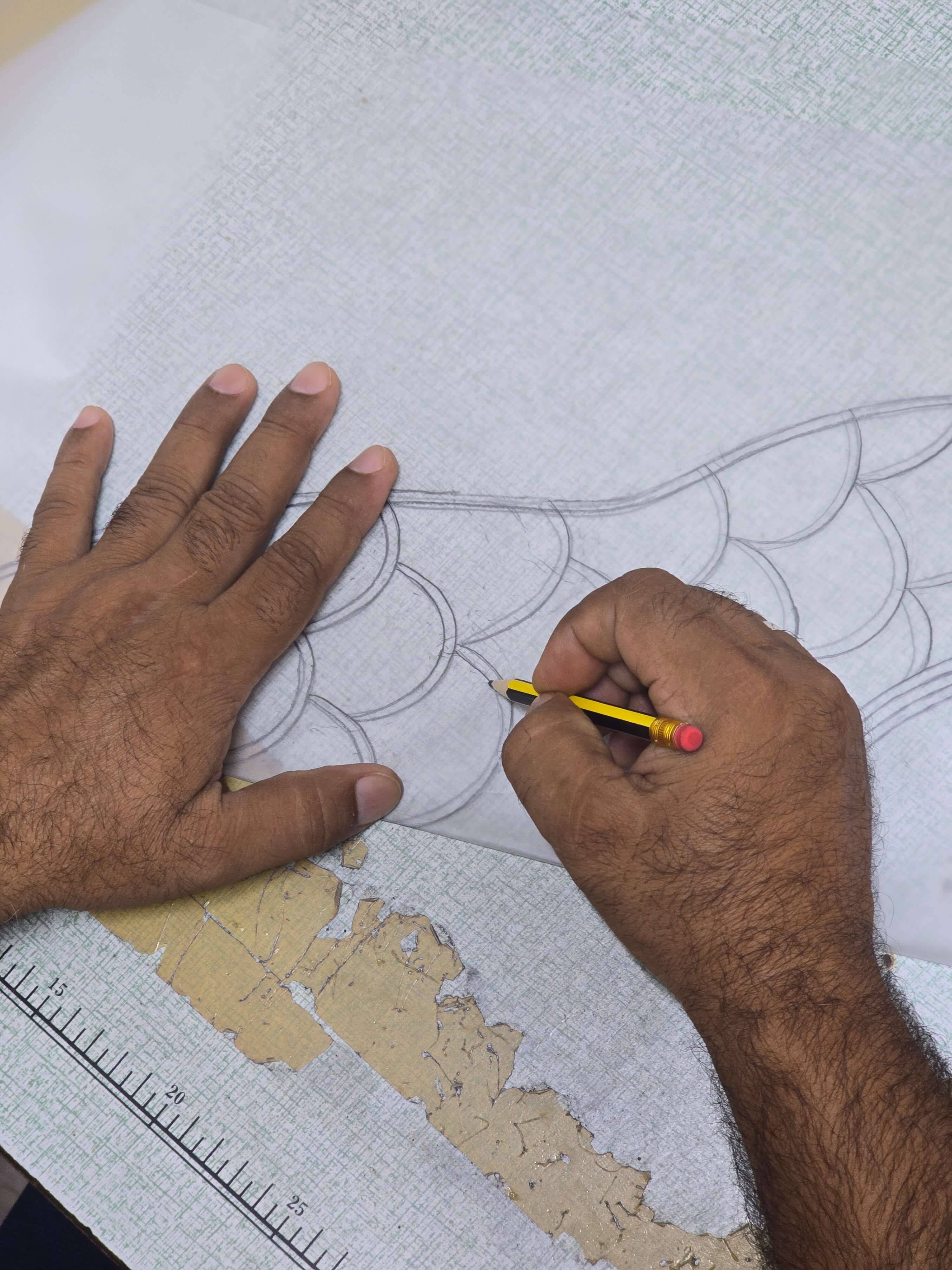 A tailor sketching a pattern with a pencil